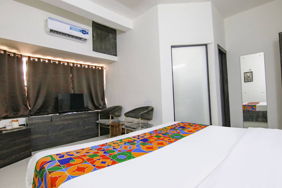 A hotel room with a bed, a desk, a chair, and a large mirror.