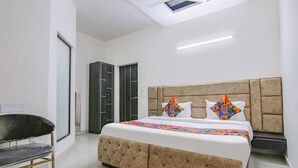 A modern bedroom with a large bed, a bench, and a wardrobe. - Fabhotel The Nation (Mohali)