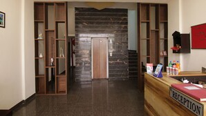A reception area with a marble wall, wooden shelving, and a reception desk. - Fabhotel The Nation (Mohali)