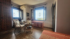 A room with wicker furniture, a glass table, a radiator, and a window with bars. - Villa - Casa del Sol! Detached villa with pool, outdoor terraces near the beach! (Nerja)
