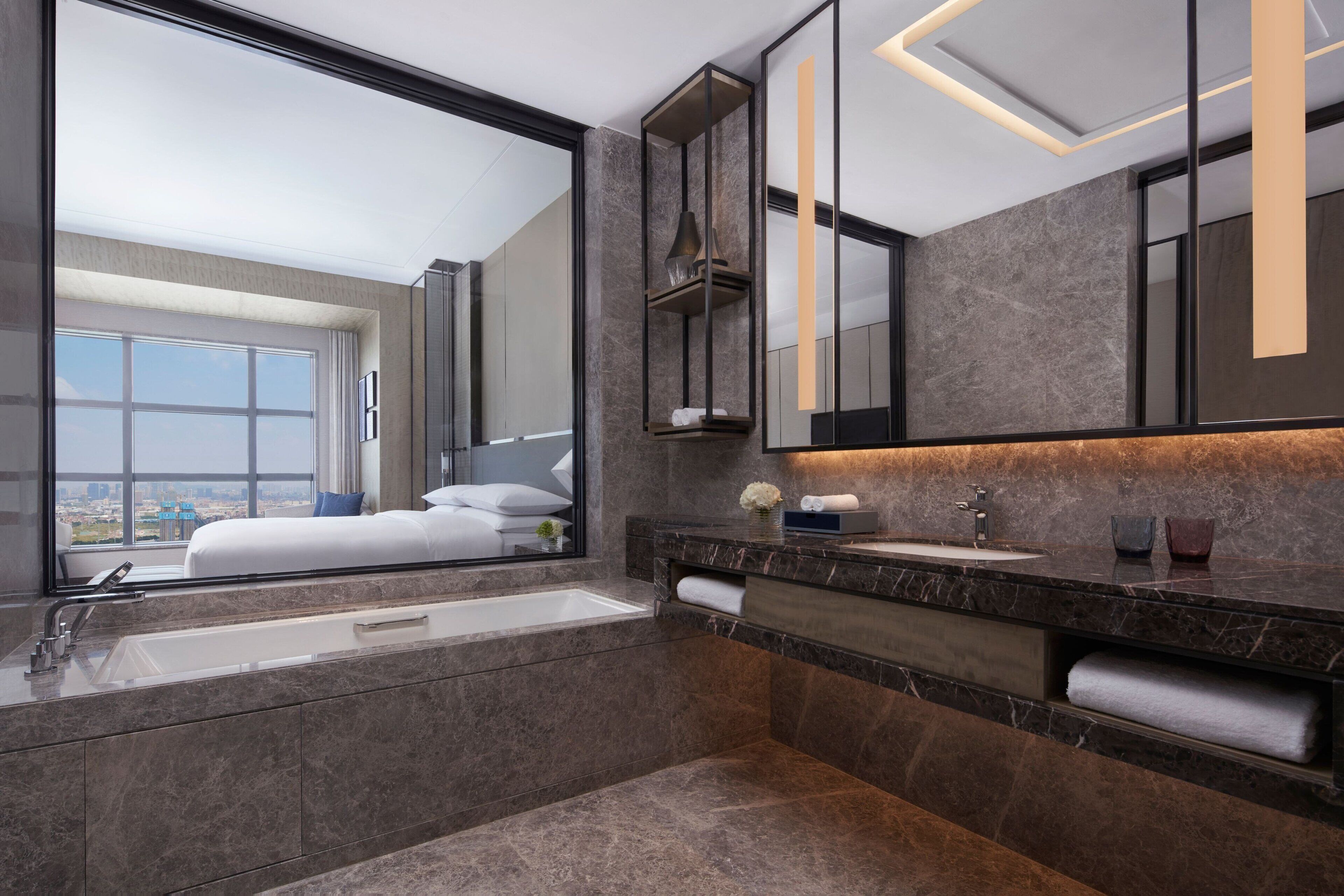A modern bathroom with a large mirror, a bathtub, and a vanity with a sink.
