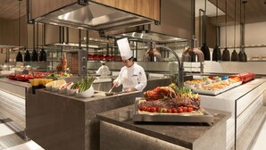 A modern kitchen with chefs preparing food, stainless steel appliances, and a buffet setup. - Foshan Marriott Hotel (Foshan)