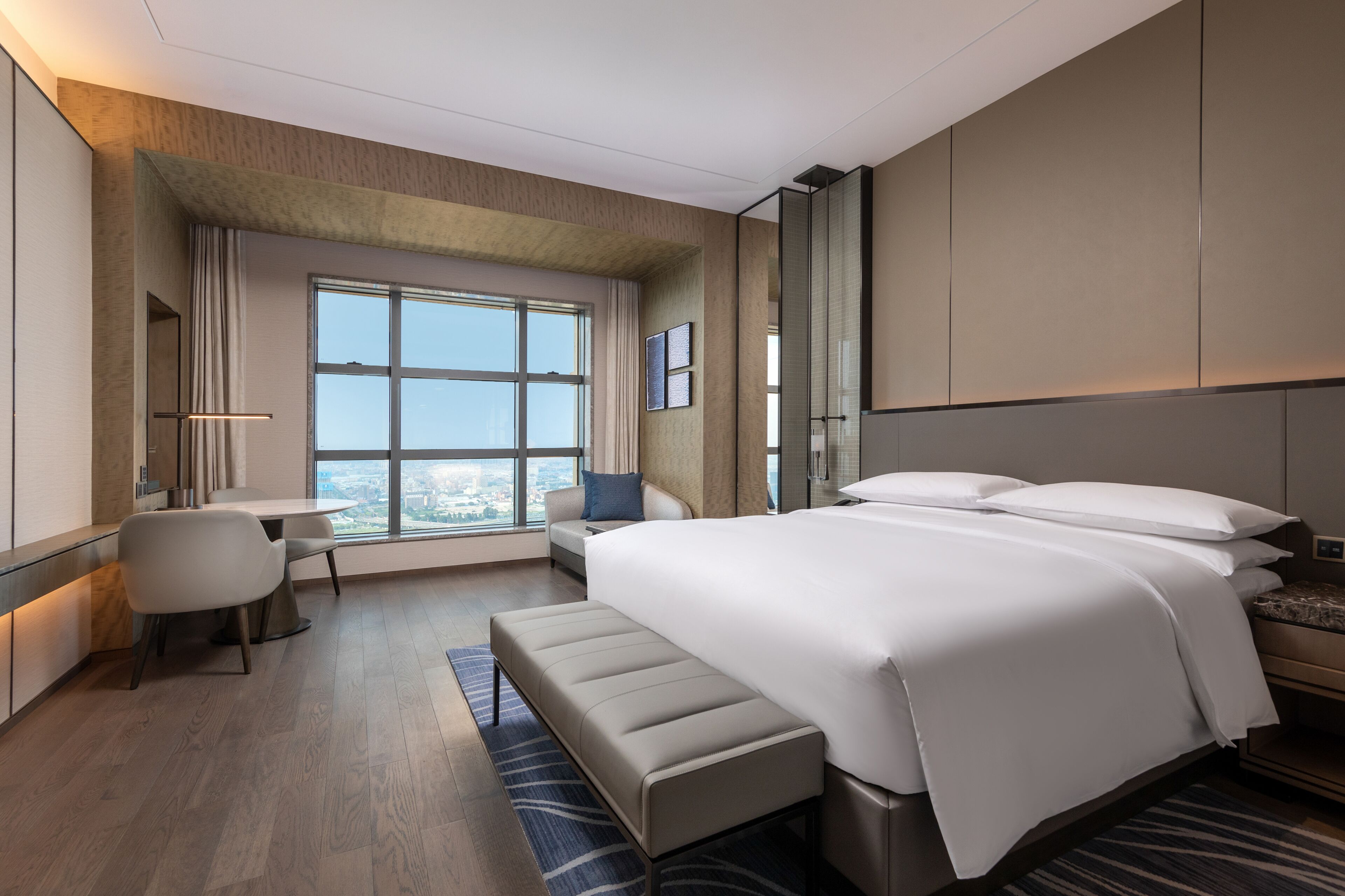Une chambre d’hôtel moderne, dotée d’un grand lit, d’un bureau et offrant une vue sur la ville.