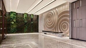 A spacious lobby with a reflective marble floor, a vertical garden wall, and a modern wall design with concentric circles. - Foshan Marriott Hotel (Foshan)