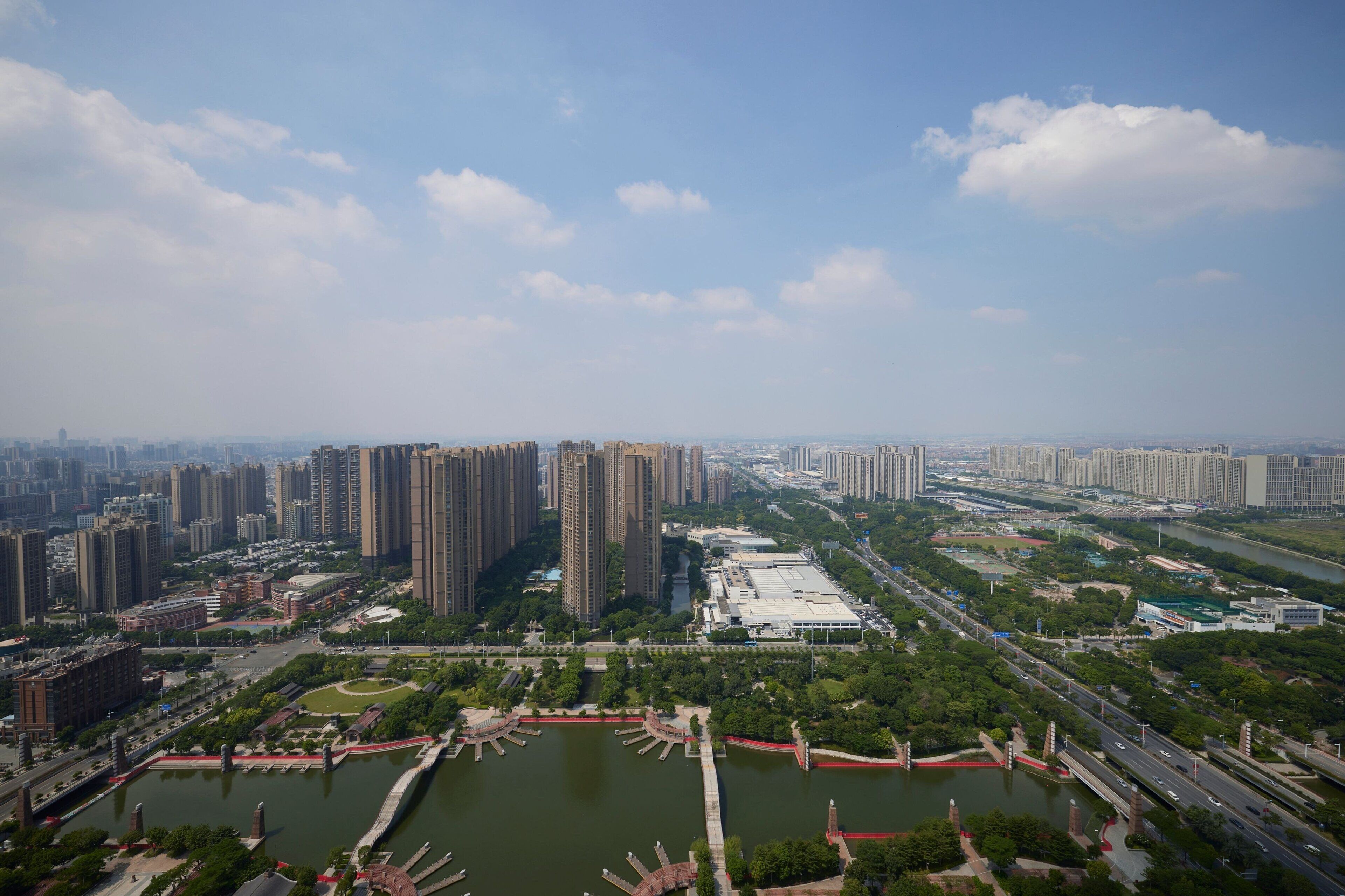 An aerial view of a cityscape with high-rise buildings, a river, and green spaces.