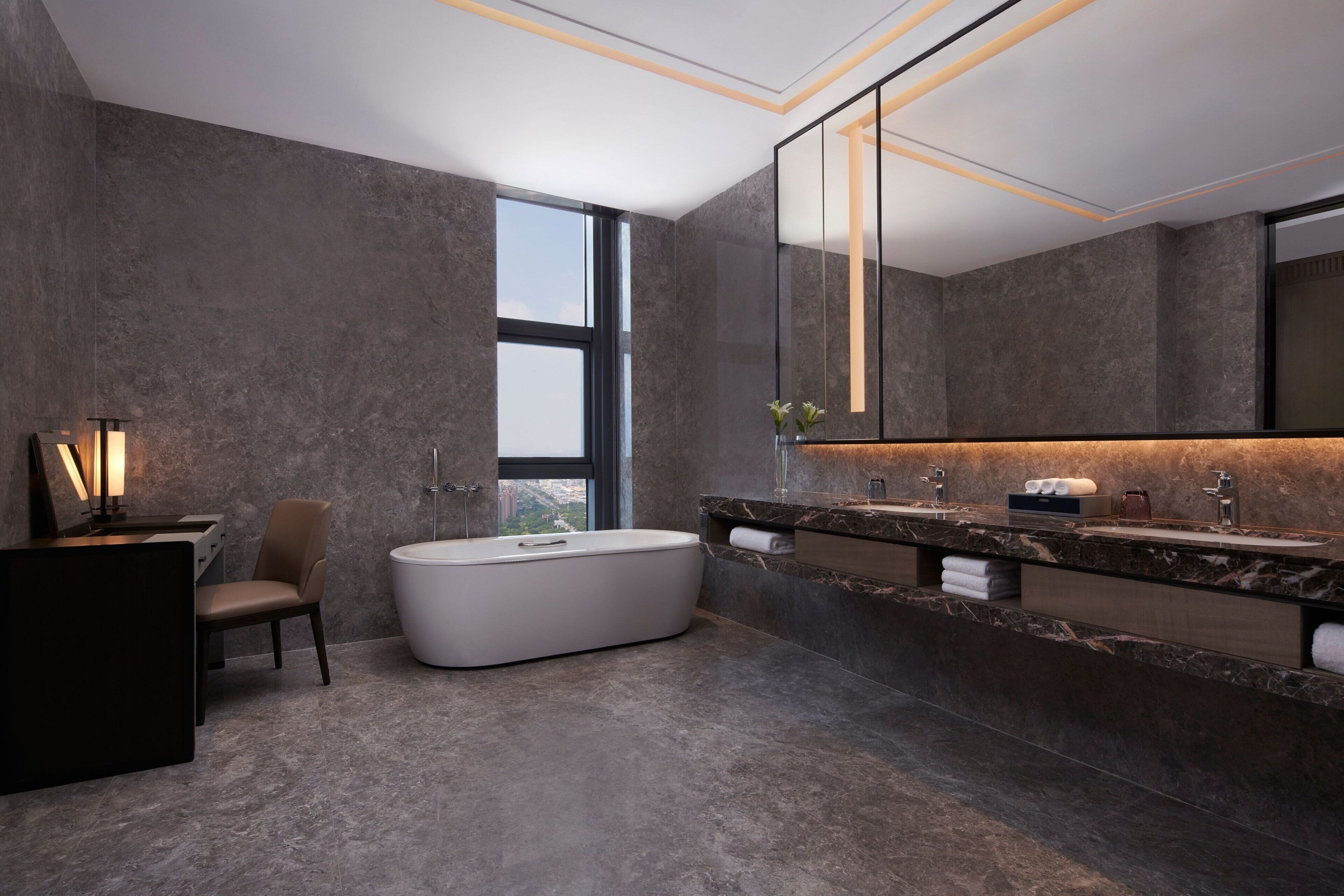 Un baño moderno con una bañera grande, un tocador con dos lavamanos y un espejo amplio.
