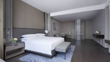 Une chambre d’hôtel moderne avec un grand lit, un bureau, une chaise et une petite table sur laquelle est posé un vase de fleurs.