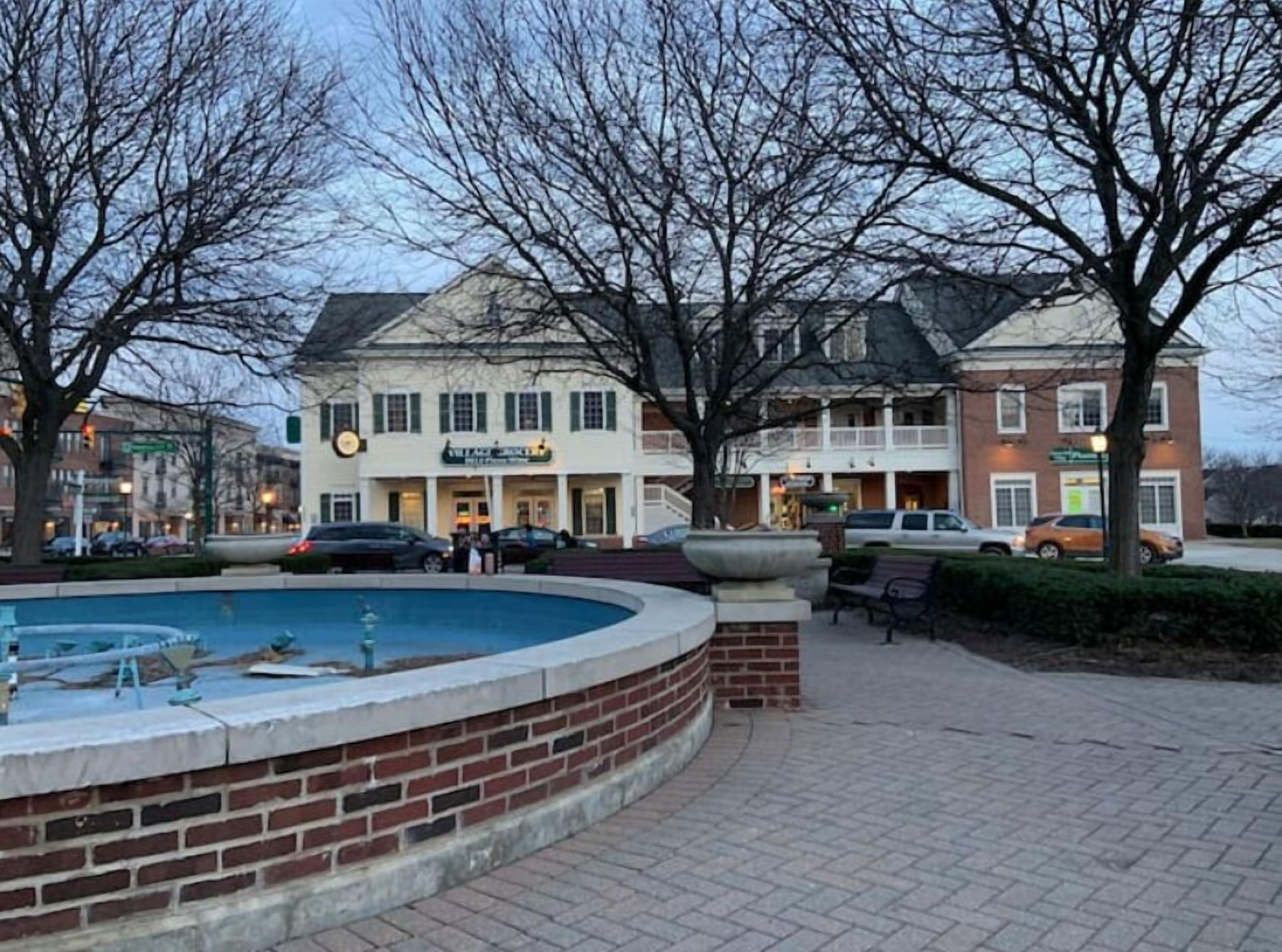 A public square with a fountain, a brick wall, and a building with a sign that reads "The Inn".