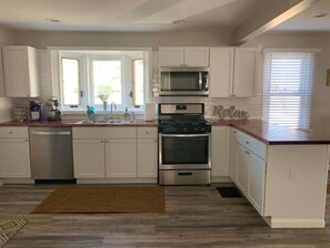 A modern kitchen with white cabinets, a stainless steel stove, a microwave, and a dishwasher. - Perfect for a family of 4 in a village setting! (Canton)