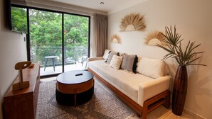 A modern living room with a sofa, a coffee table, and a large window with a view of greenery. - Charming Authentic Mexican Hideaway in Roma Norte (Mexico City)
