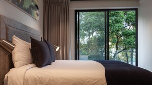 A neatly made bed with a headboard, a large window with a view of trees, and a painting on the wall. - Embrace the Now: 203 Industrial's Sunlit Serenity Awaits (Mexico City)