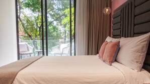 A hotel room with a large bed, a view of the outdoors, and a balcony with chairs.