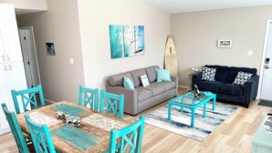 Ein Wohnzimmer mit Esstisch, zwei Sofas und einem Surfbrett.