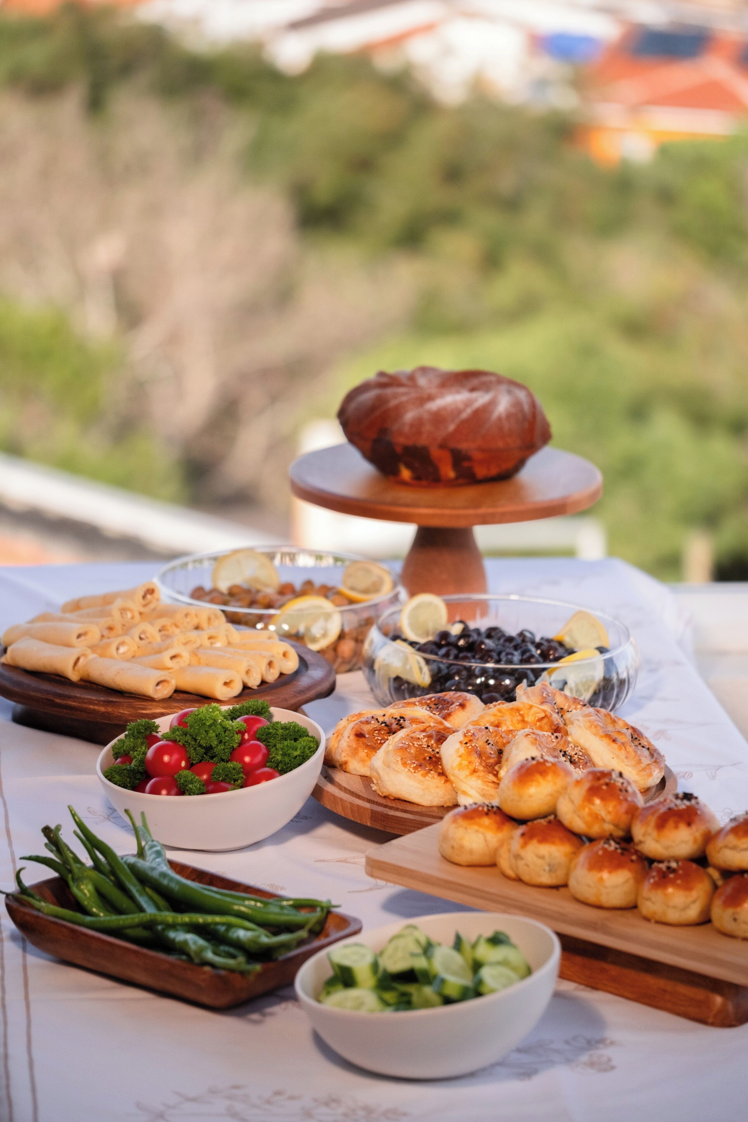 A table with various food items including rolls, a pastry, and fresh vegetables.