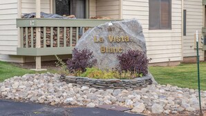 A stone sign with 'La Vista Blanc' engraved, a stone wall with plants, and a building with a balcony and window. - Large and Comfortable Condo w/ Loft (Mammoth Lakes)