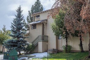 Une maison à deux étages avec un porche à l’avant, un escalier et une pelouse recouverte de neige.