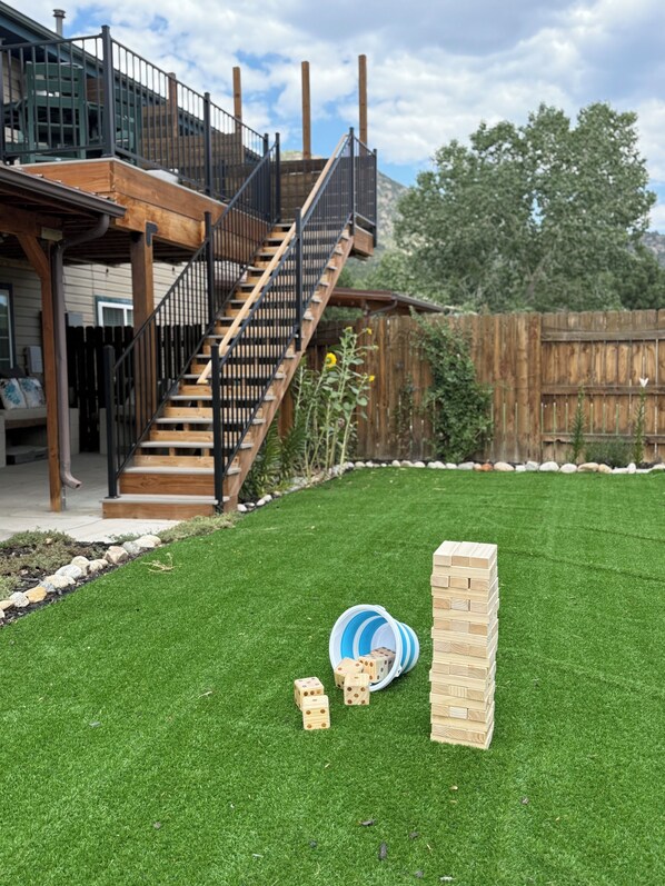 Un patio trasero con una terraza de madera, una escalera y un área cercada.