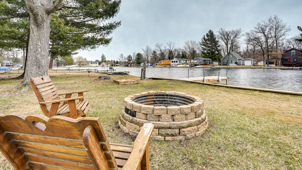A lakeside park with a fire pit and wooden chairs. - Sand Lakefront Retreat | Private Dock & Fire Pit (Harrison)