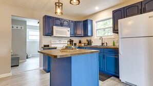 A modern kitchen with blue cabinets, a central island, a white refrigerator, and a microwave. - Sand Lakefront Retreat | Private Dock & Fire Pit (Harrison)