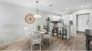 Une cuisine moderne avec des meubles blancs, un îlot central en bois et un luminaire suspendu.