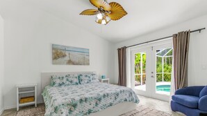 Une chambre à coucher comprenant un lit, une table de chevet, une chaise et une vue sur une piscine, visible à travers une porte vitrée.