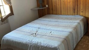 A bedroom with a wooden headboard, a bed with a striped bedspread, a window with curtains, and a painting on the wall. - House la franqui (Occitanie)