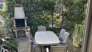 An outdoor patio with a table and chairs, a grill, and a bicycle. - House la franqui (Occitanie)