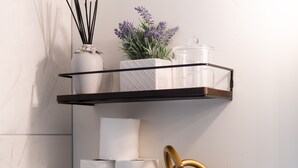 Prateleira fixada na parede com três níveis, cada um exibindo objetos diferentes.
