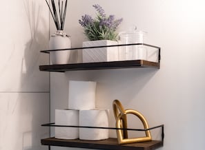 A wall-mounted shelf with three tiers, each holding different items.