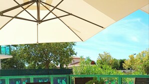 An outdoor patio with a table covered by a tablecloth with a nautical theme, a potted plant, and a bottle of wine. - Serignan-Canal du midi. Spacious apartment in luxury apartment complex. Full A/C (Sérignan)