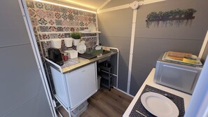 A compact kitchenette with a coffee maker, a small fridge, and a sink.