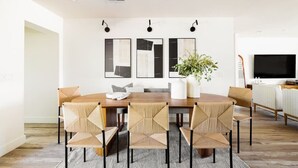 A modern dining area with a wooden table, six woven chairs, and three abstract paintings on the wall. - Family-Friendly Retreat with Heated Pool (Scottsdale)
