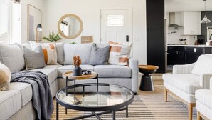A modern living room with a sectional sofa, a glass coffee table, and a kitchen in the background. - Family-Friendly Retreat with Heated Pool (Scottsdale)