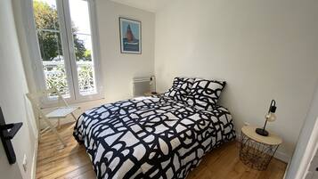 Une chambre à coucher avec un lit, une chaise, une petite table et un radiateur.