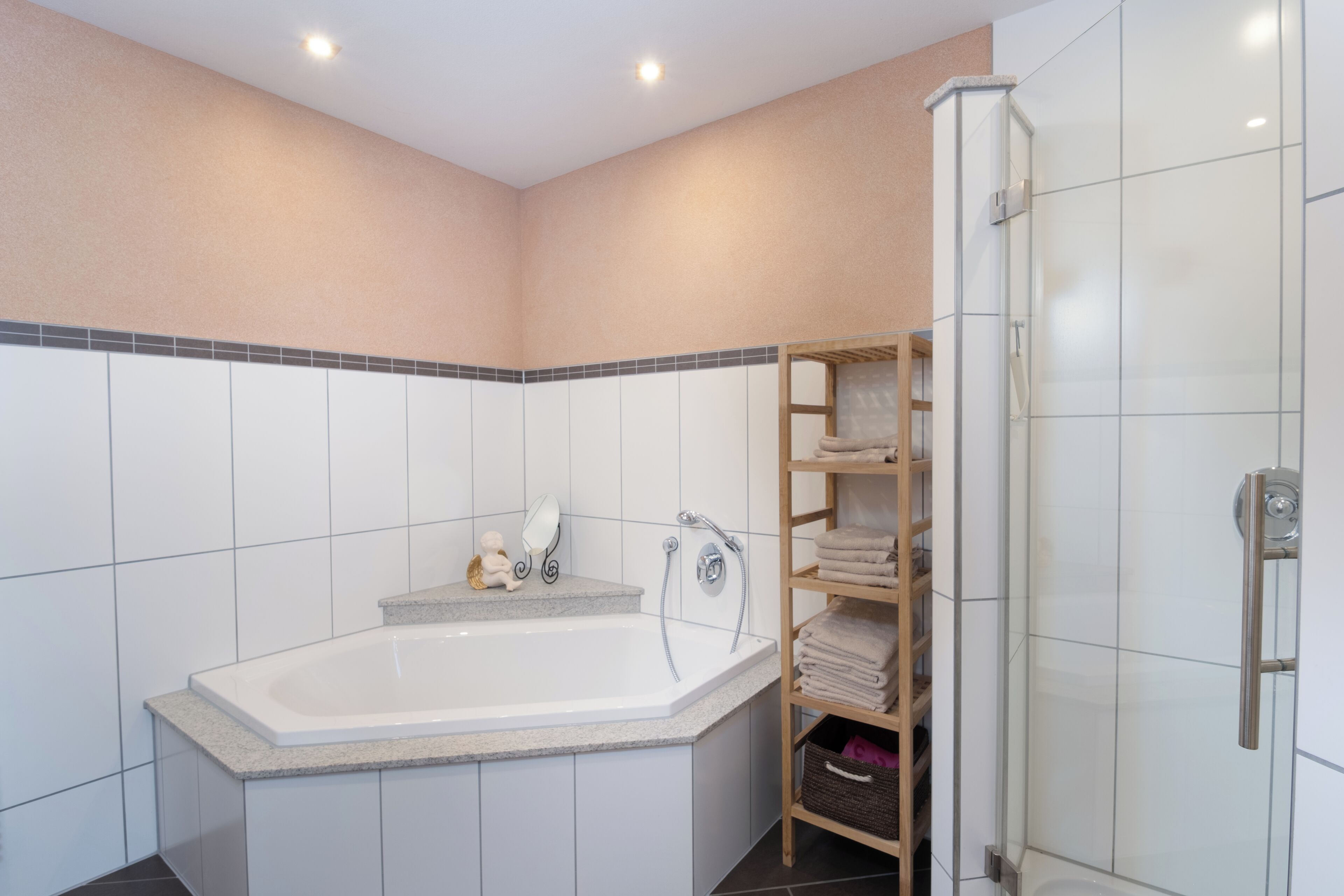 A modern bathroom with a freestanding bathtub, a glass shower enclosure, and a built-in shelf with towels.