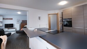 Una cocina moderna con una isla grande, electrodomésticos integrados y una zona de comedor con sofá y mesa.