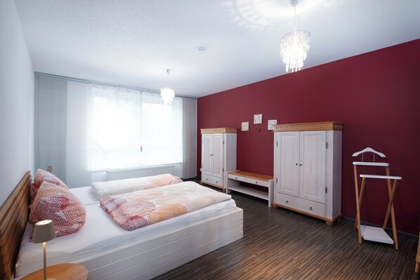 A bedroom with a bed, two wardrobes, a bedside table, and a hanging light fixture. - Vacation apartment close to nature in the Swabian forest (Spraitbach)