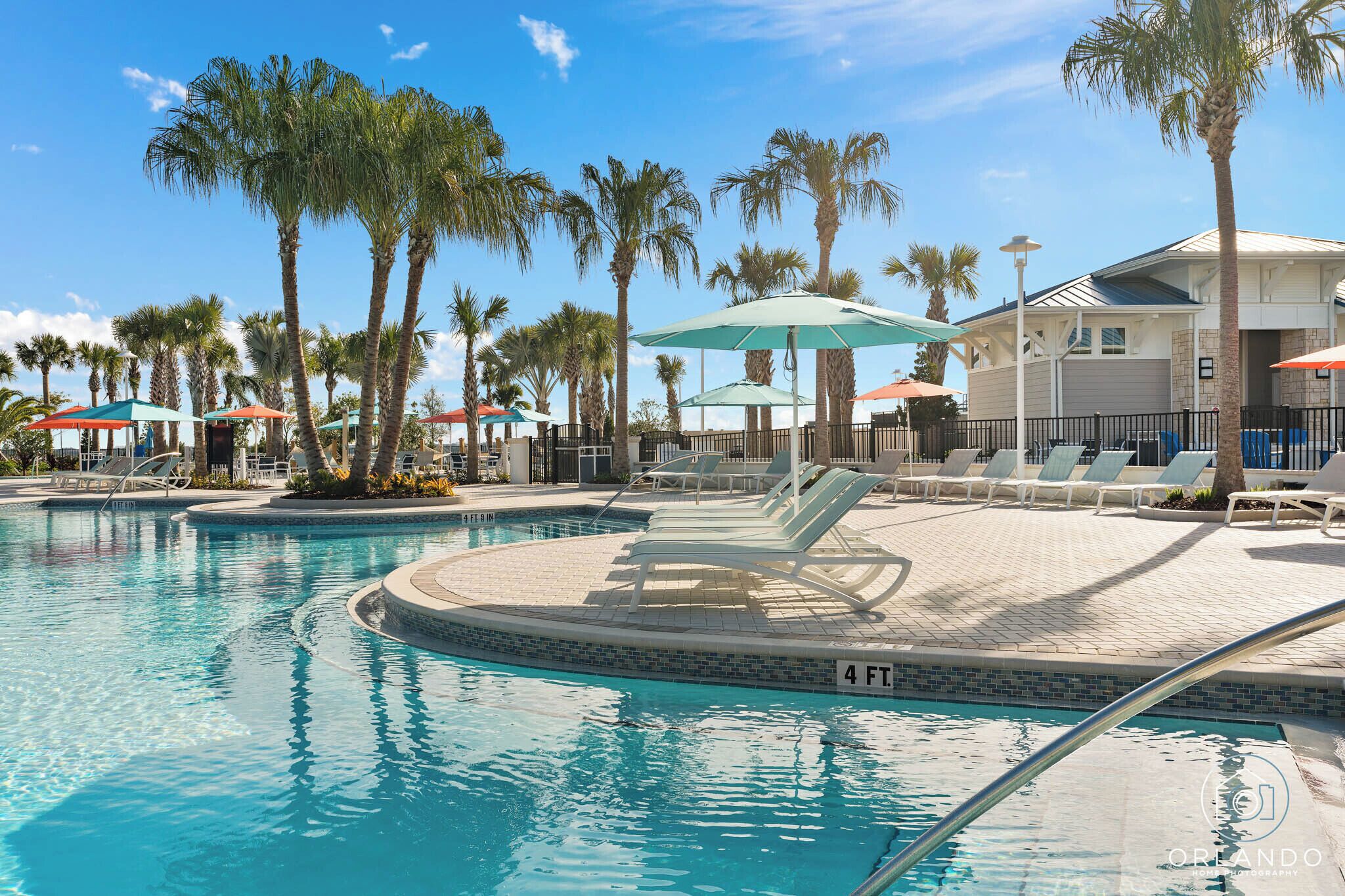A swimming pool with lounge chairs and umbrellas, surrounded by palm trees.