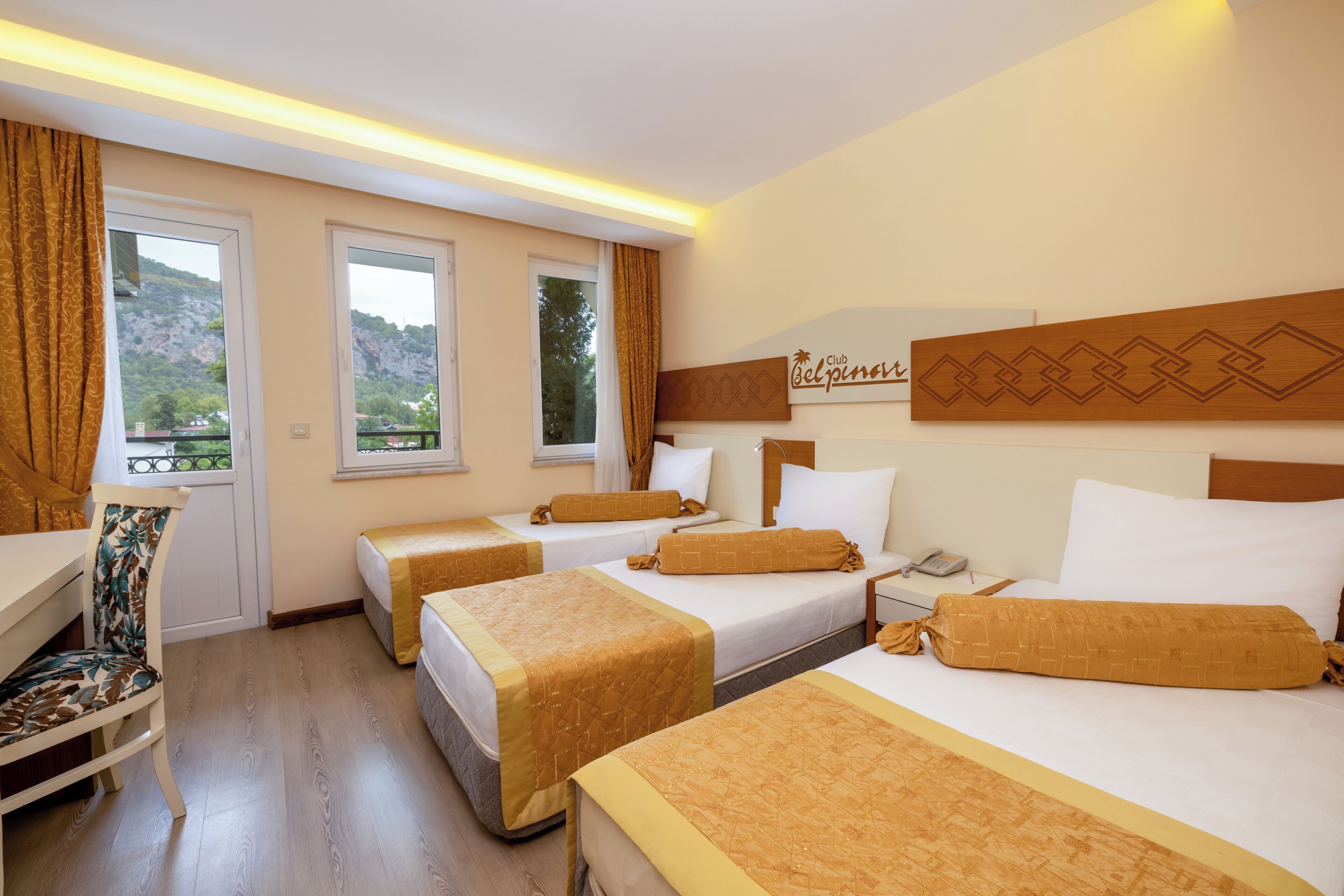 Une chambre d’hôtel avec trois lits, un bureau et une chaise.