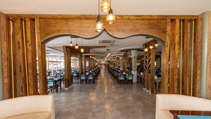 Um restaurante espaçoso com tetos de madeira altos e várias mesas para refeições.