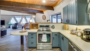 Een moderne keuken met een ingebouwde oven, een koffieapparaat, en een eethoek met een ronde tafel en stoelen.