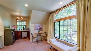 A cozy room with a large window, a bench, a dining area with a table and chairs, and a kitchen area with a refrigerator and a sink. - 'Lakeside Bear Lodge' Studio: 9 Mi to Bass Lake! (Wishon)