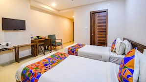 A hotel room with two beds, a desk, a chair, and a television on the wall. - Fabhotel Royal Crystal (Bhubaneshwar)