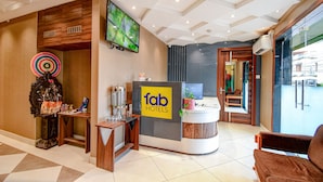 A hotel reception area with a modern design, including a reception desk, a television, and a decorative wall piece. - Fabhotel Royal Crystal (Bhubaneshwar)