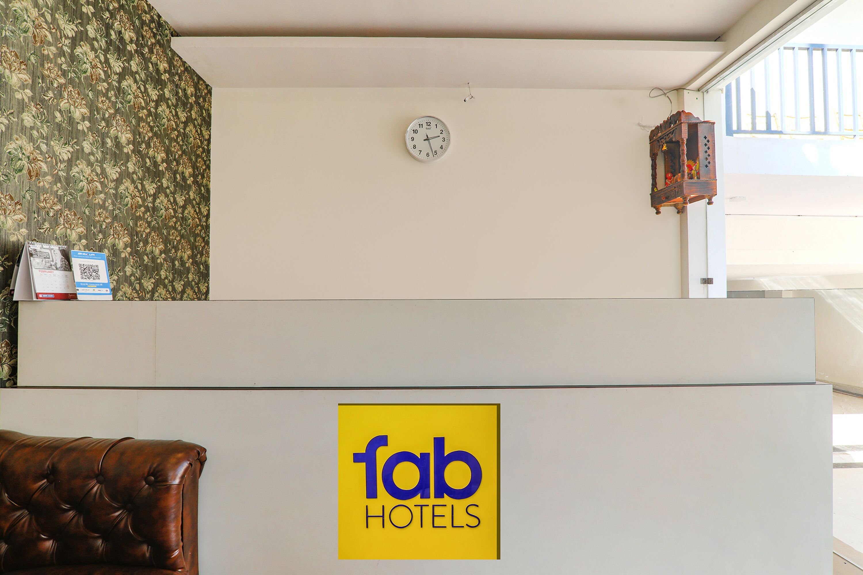 A reception desk with a clock, a wall clock, and a sign for Fab Hotels.
