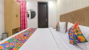 A hotel room with a bed, a wardrobe, a mirror, and a door. - Fabhotel The Comfort (Prayagraj)