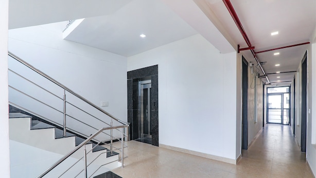 A modern interior with a staircase, elevator, and a long hallway. - Fabhotel The Comfort (Prayagraj)