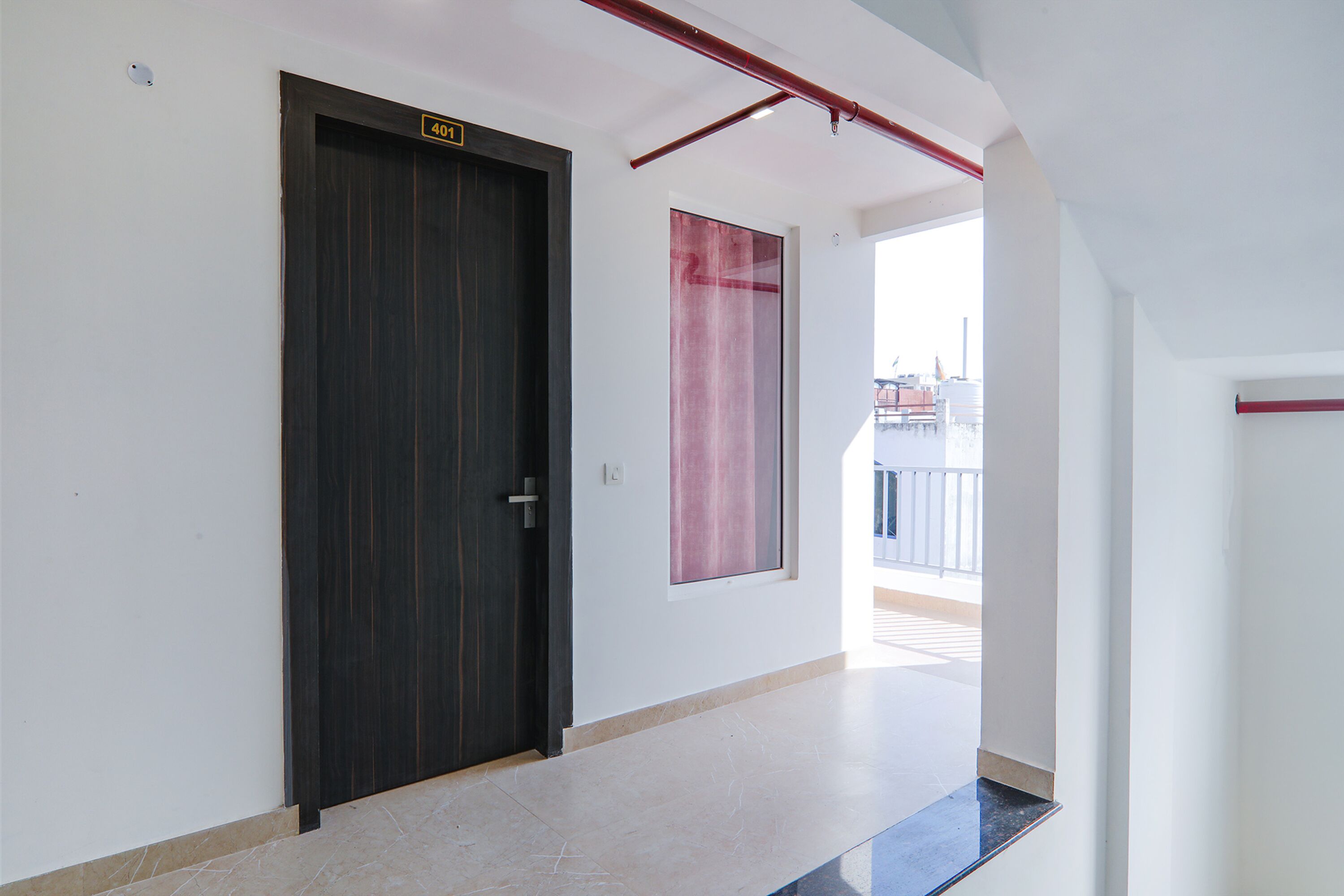 A hallway with a dark wooden door marked "401", a large window with a pink curtain, and a view of buildings outside.