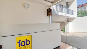 A hotel reception area with a clock, a sign for 'Tab Hotels', and a view of the outdoor balcony. - Fabhotel The Comfort (Prayagraj)