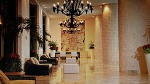 A lobby with a chandelier, sofas, and potted plants.